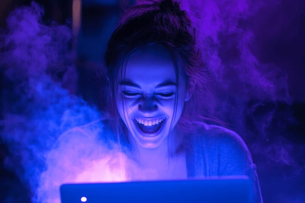 Chica frente a un ordenador, sonriendo mientras usa la IA en un entorno de humo y colores lilas, reflejando poder y creatividad.